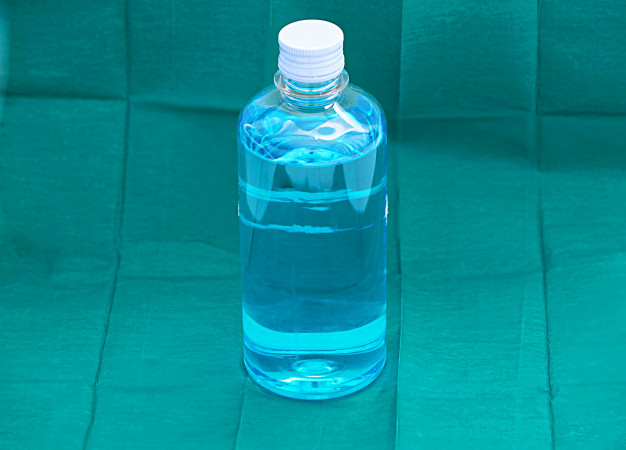 Blue ethyl alcohol liquid in plastic transparent bottle on green surgery background Premium Photo