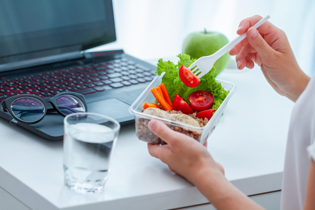 描述: Woman eating food from take away lunch box at workplace during lunch break. container food at work Premium Photo