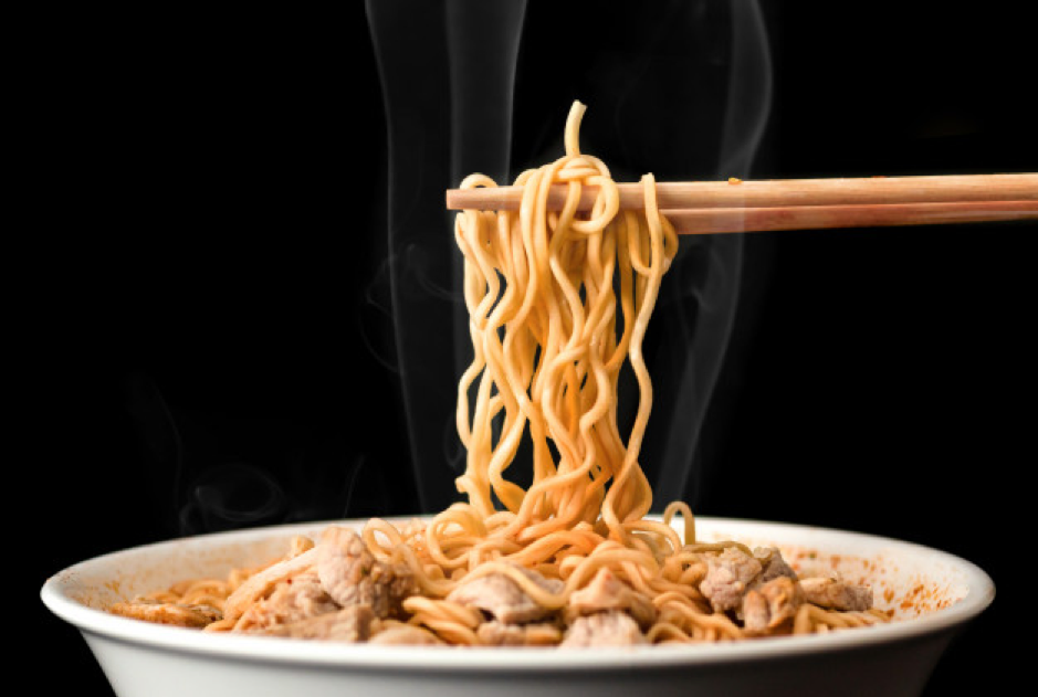 Chopsticks pick up tasty noodles with smoke on dark background. ramen in white bowl. Premium Photo
